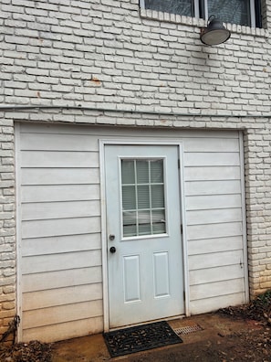 A white garage door with a window, a metal door handle, and a doormat. - Private office space plus studio vibe bedroom/ living room. Full kitchen W&Dryer (Mableton)