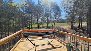 A wooden deck with a hammock and potted plants.