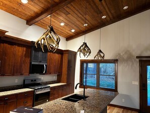 A kitchen with wooden cabinets, granite countertops, a stainless steel stove, and a window with blinds. - Cozy 2BR Downstairs Suite - TV & Grill Access (Hamburg)