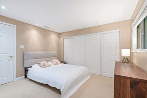 A bedroom with a bed, a nightstand, a lamp, a wardrobe, and a window. - Spacious 4BR North Van Home - Perfect for Groups (North Vancouver)