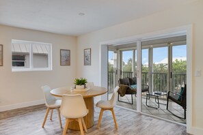 A dining area with a round table, chairs, and a plant. - Sanibel Arms A8- Gorgeous Condo Steps to Beach (Sanibel)