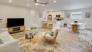Un salon moderne avec un téléviseur à écran plat, un canapé, une table basse et un tapis à motifs.