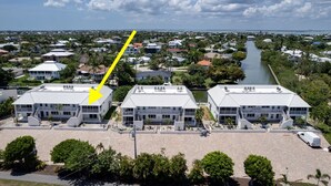 Vue aérienne d’un quartier résidentiel avec une rivière, des maisons et un grand bâtiment doté d’un toit plat et de nombreuses fenêtres.