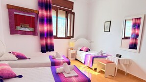 Ein Hotelzimmer mit zwei Betten, einem Schreibtisch, einem Stuhl, einem Nachttisch und einem Fenster mit Vorhängen.