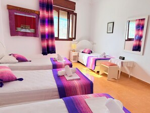Une chambre d’hôtel avec deux lits, un bureau, une chaise, une table de chevet et une fenêtre avec des rideaux.