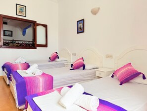 Ein Hotelzimmer mit zwei Betten, jeweils mit weißem Kopfteil, einem Nachttisch und einem an der Wand befestigten Spiegel.