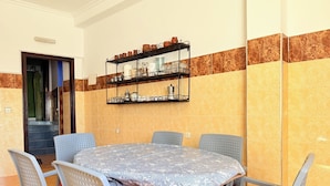 Ein Essbereich mit einem runden Tisch, sechs Stühlen und einem Wandregal mit Geschirr.