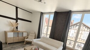 A modern living room with a sofa, a coffee table, a TV stand, and a large window with curtains. - T2 bright hyper center (Châlons-en-Champagne)