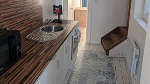A narrow kitchen with a wooden countertop, a stainless steel sink, and patterned floor tiles. - T2 bright hyper center (Châlons-en-Champagne)