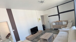 A modern living room with a sofa, a TV, and a dining area. - T2 bright hyper center (Châlons-en-Champagne)