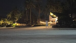 Una playa con palmeras y un edificio con luces.