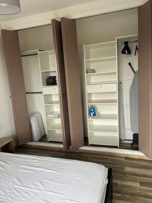 Un dormitorio con cama, un armario de puertas abiertas y un baño con ducha.