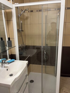 Un baño moderno con cabina de ducha de vidrio, un lavamanos blanco y jabón azul, y un espejo.