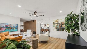 Ein modernes Wohnzimmer mit einer Couch, Sesseln, einem Couchtisch und einem Fernseher.