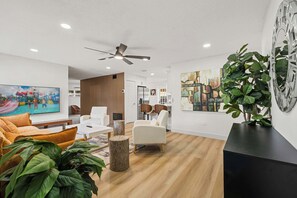 Ein modernes Wohnzimmer mit einer Couch, Sesseln, einem Couchtisch und einem Fernseher.