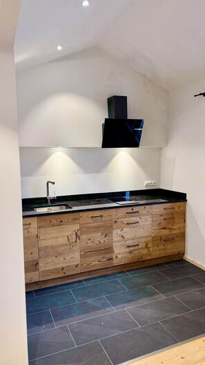 Una cucina moderna con un armadietto in legno, un piano di lavoro nero e un piano cottura integrato.