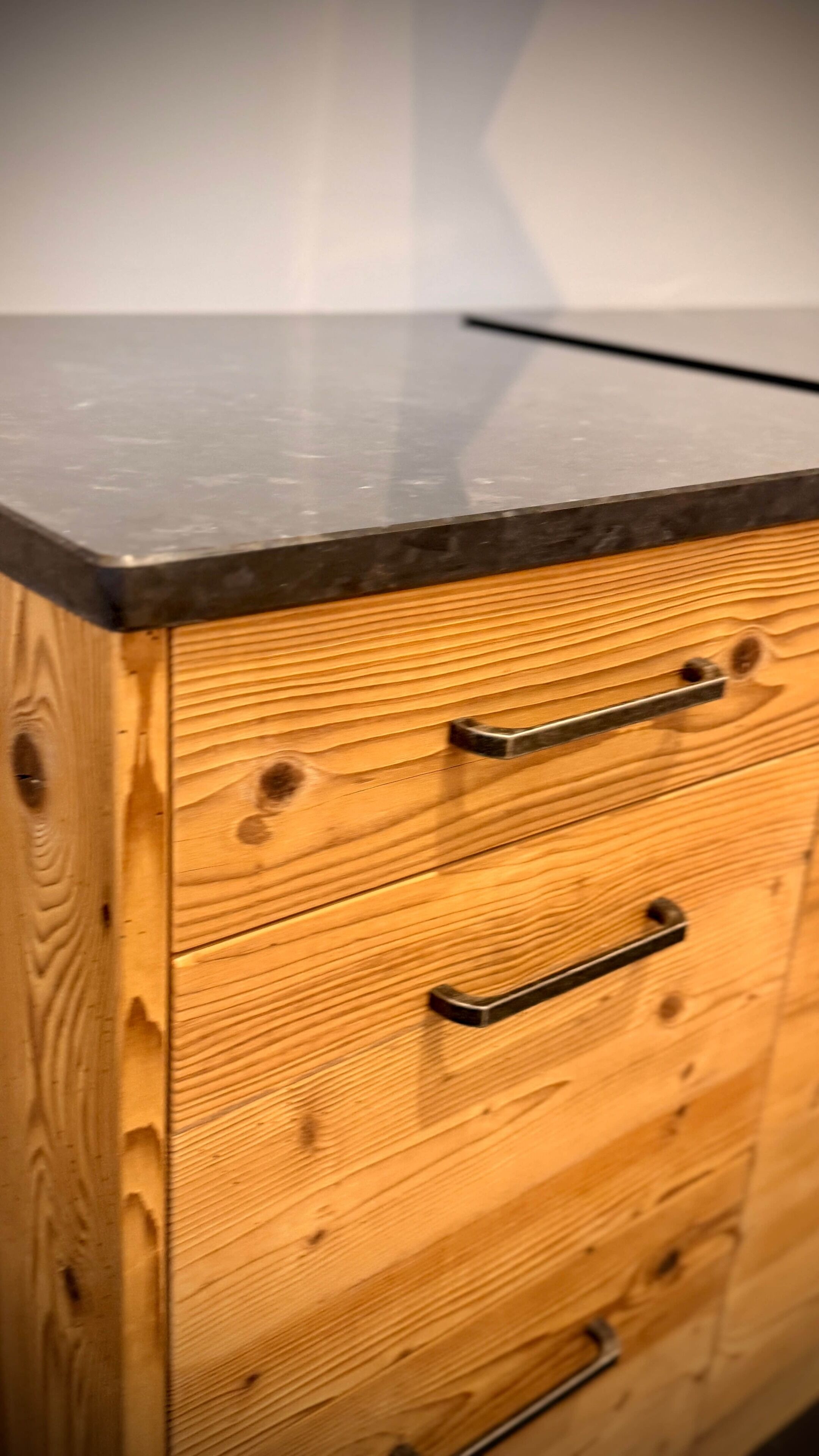 Un meuble en bois avec des tiroirs et un plan de travail noir.