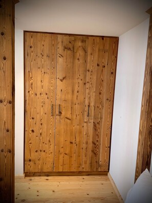 Ein Zimmer mit einem großen, hölzernen Kleiderschrank, einer weißen Wand und einem Holzboden.