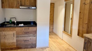 Una cocina con armarios de madera, una campana extractora de acero inoxidable, encimera negra y suelo de madera.