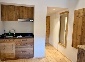 Eine Küche mit Holzausstattung, einer Edelstahl-Dunstabzugshaube, einer schwarzen Arbeitsplatte und einem Holzboden.