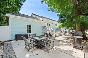 A patio with a metal table and chairs, a barbecue grill, and a staircase leading to a deck. - "Coastal Belle" By Beach Star Near Marsh Walk (Murrells Inlet)