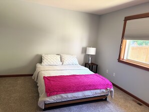 A bedroom with a bed, a nightstand with a lamp, a window with blinds, and a carpeted floor. - Quite snohomish/Everett retreat near Mill-creek and Bothell. (Everett)