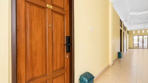 Una puerta de madera con un cartel, una mirilla y un cubo de basura a su lado.