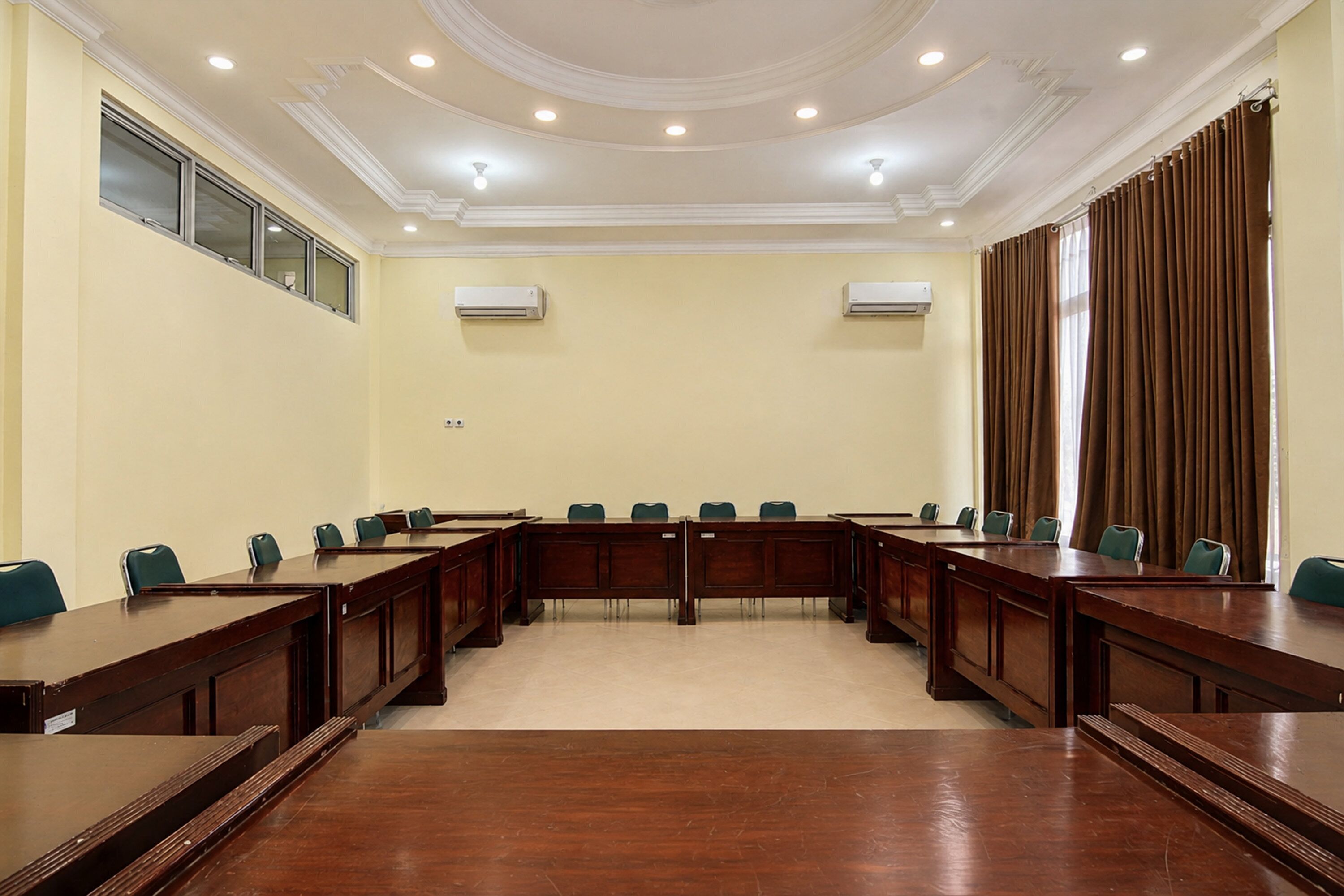 A conference room with a long table, chairs, and two air conditioning units on the walls.
