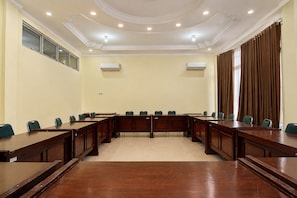 A conference room with a long table, chairs, and two air conditioning units on the walls.