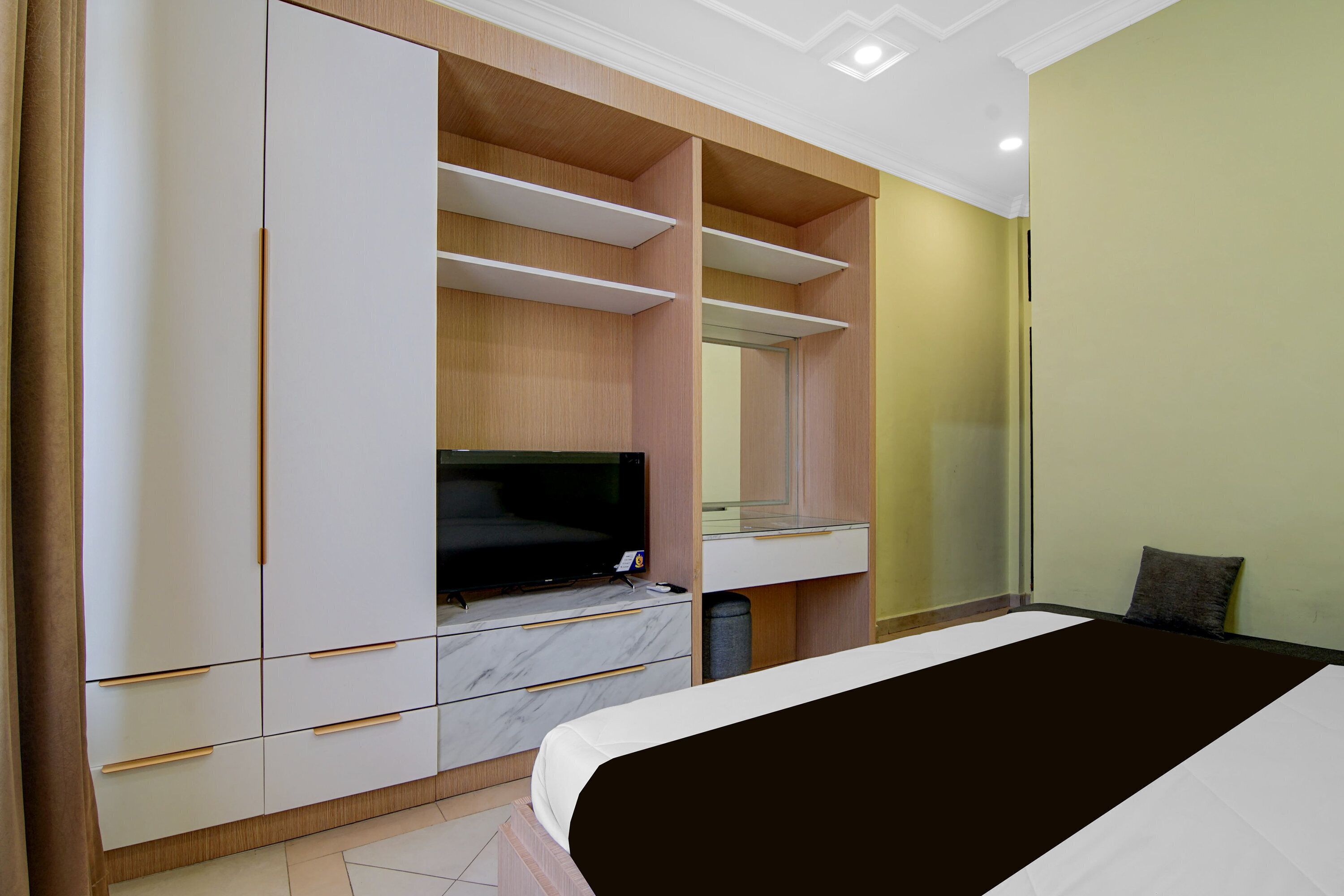 Un dormitorio con cama, televisión, espejo y armario.