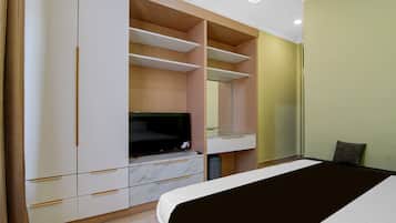 Un dormitorio con cama, televisión, espejo y armario.