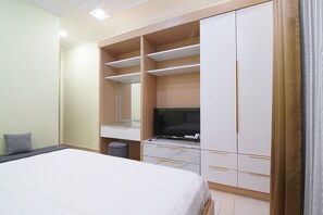Ein Schlafzimmer mit Bett, Fernseher, Kleiderschrank und Schreibtisch.