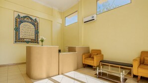Un área de recepción con mostrador, dos sillones, una mesa de centro de vidrio y un equipo de aire acondicionado en la pared.
