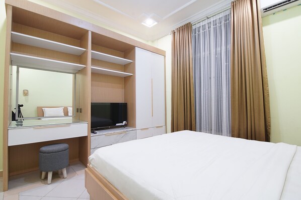 Une chambre d’hôtel comprenant un lit, une télévision, un bureau avec un miroir et une armoire.