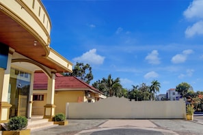 A hotel entrance with a covered walkway, a red-tiled roof, and a clear blue sky.