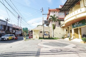 Vista de la calle con un cartel de J&T Cargo, un edificio con balcón y una scooter estacionada.