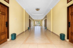 A long, narrow hallway with wooden doors on both sides, a tiled floor, and a ceiling with a central light fixture.