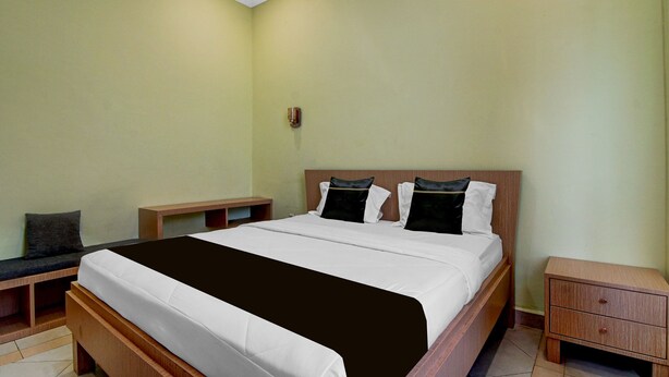 Una habitación de hotel con cama, mesitas de noche y un armario de madera.