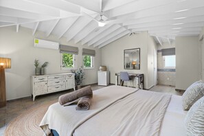A bedroom with a bed, a desk, a chair, a mirror, and a ceiling fan. - Vrbo Property (Kralendijk)