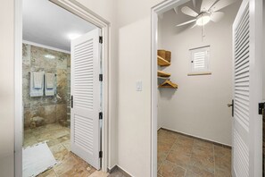 Een badkamer met een douche, plafondventilator en handdoekrek.