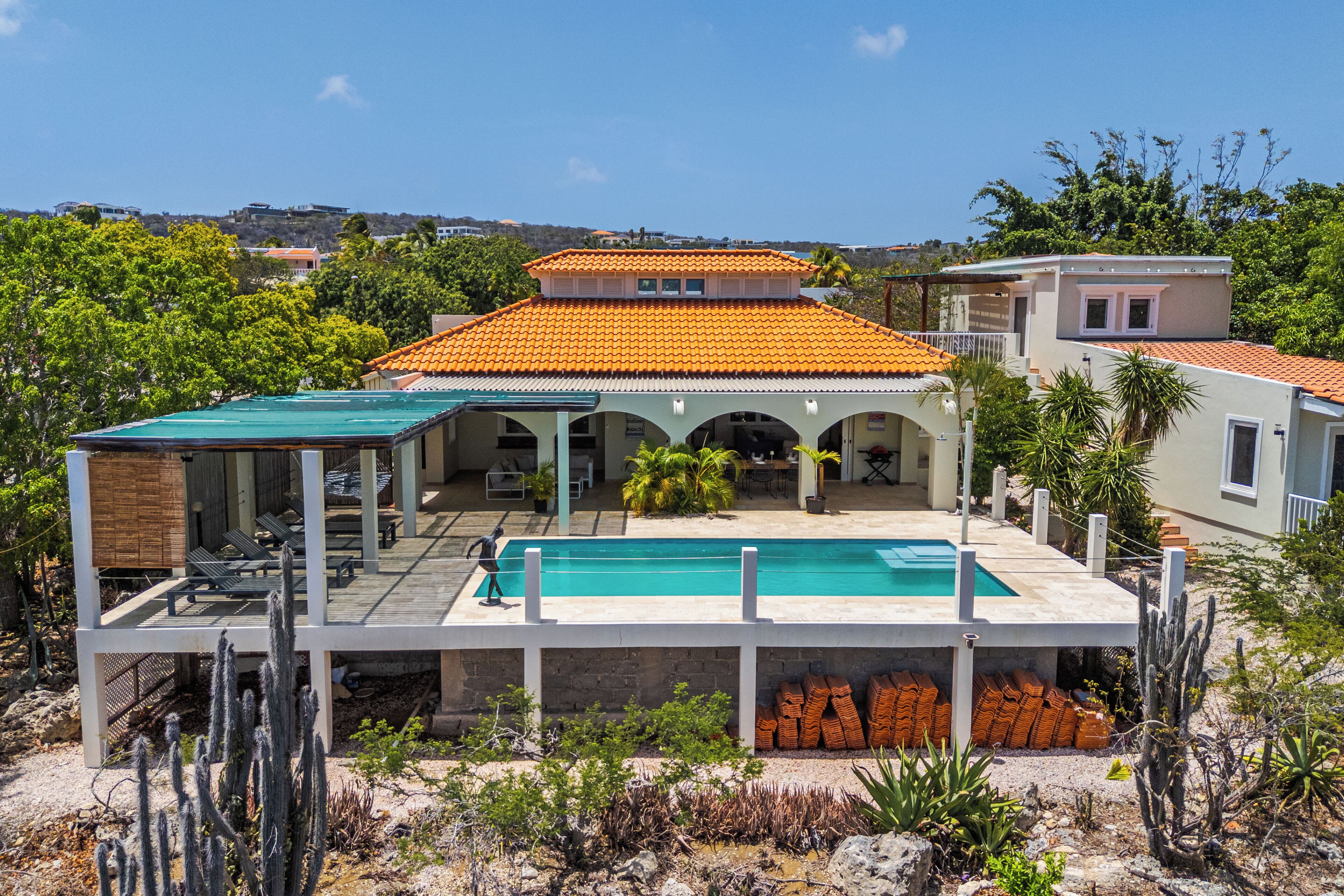 A two-story house with a swimming pool, outdoor seating, and a view of the surrounding landscape.
