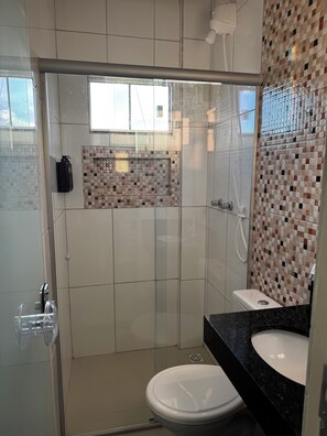 A modern bathroom with a glass-enclosed shower, a white toilet, and a black countertop with a sink.