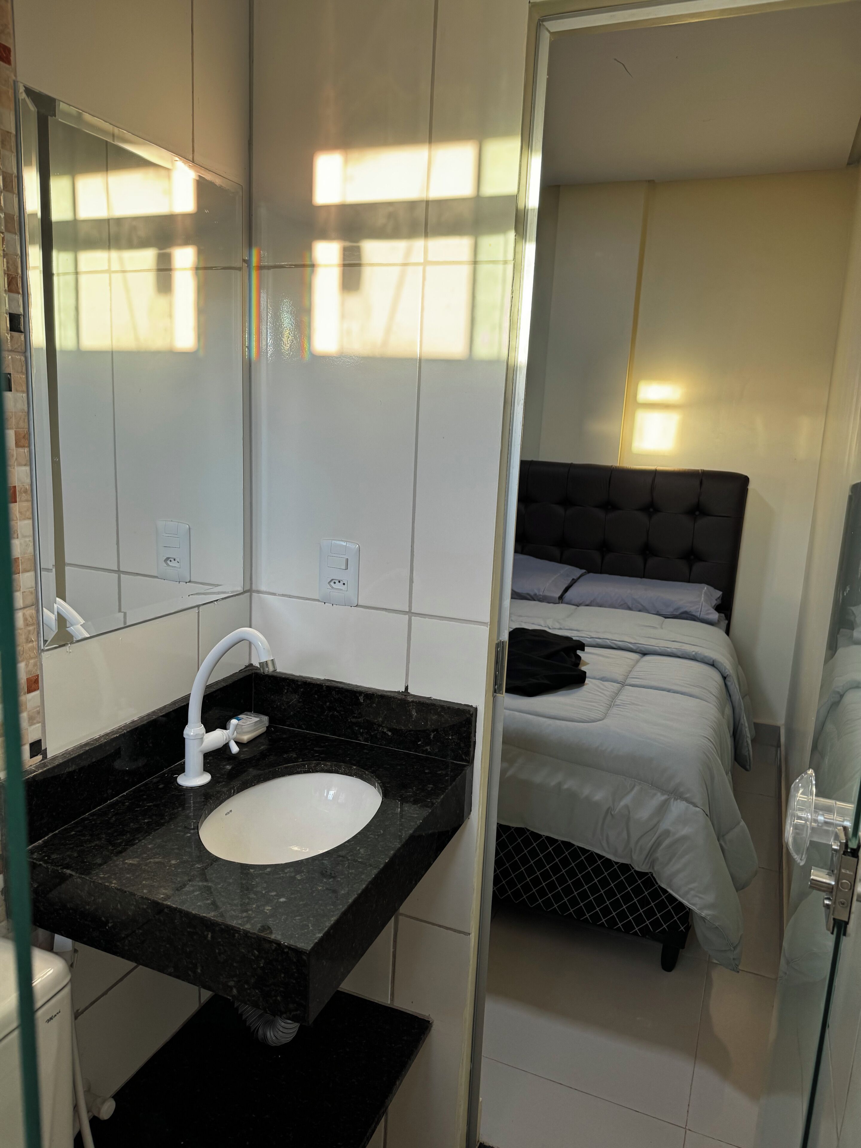 A modern bathroom with a white sink, a mirror, and a black countertop.