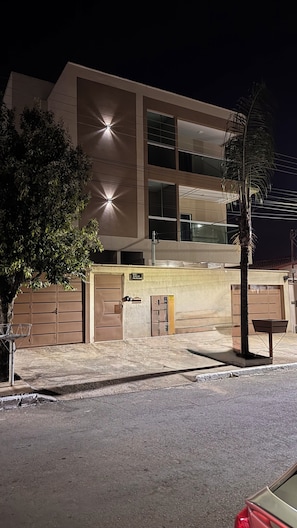 Un edificio moderno de varios pisos, con amplios ventanales y un estacionamiento que incluye una palmera.