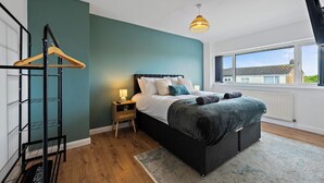 Une chambre à coucher avec un lit, une table de chevet, une lampe et une vue sur l’extérieur.