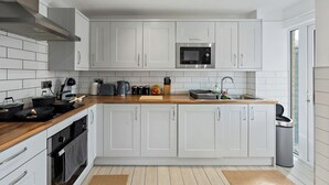 Une cuisine moderne avec des meubles blancs, un four à micro-ondes, une bouilloire et un évier.