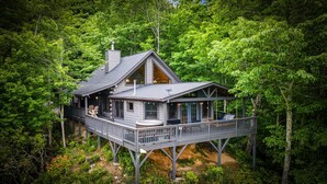 Eine Hütte mit Terrasse, großen Fenstern und einem Whirlpool.