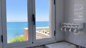 A bathroom with a view of the sea, a white sink, and a shelf with cups. - Impressive penthouse on the seafront (PEÑISCOLA)