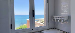 A bathroom with a view of the sea, a white sink, and a shelf with cups. - Impressive penthouse on the seafront (PEÑISCOLA)
