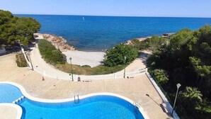 A pool area with a view of the sea, surrounded by trees and a white fence. - Impressive penthouse on the seafront (PEÑISCOLA)
